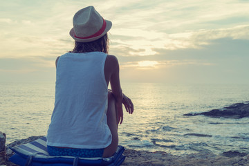 Lonesome girl watching the sunset / sunrise over sea / ocean horizon.