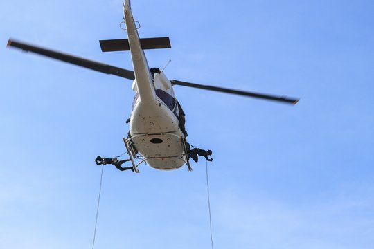 Soldier rappelling from helicopter in blue sky with blur propeller