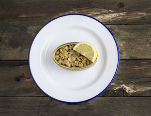 Can of cockles on a plate on rustic wooden table