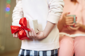 Girl hiding package with red ribbon behind her back