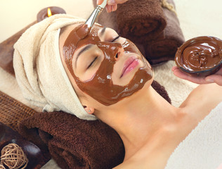 Chocolate Spa. Beautiful young woman relaxing in spa salon, applying chocolate face mask