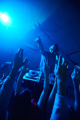 Deejay and crowd of people raving at disco