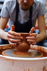 Fototapeta na wymiar Hands of clay master touching surface of rotating clay jug