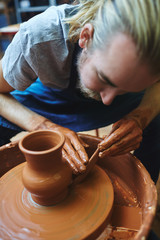 Fototapeta na wymiar Craftsman finishing up with new jug in pottery wheel