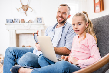 Father and daughter using devices