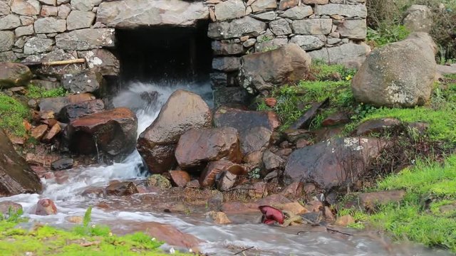 Water stream coming out of a traditional old water mill in full activity