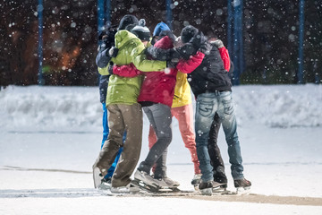 Fototapeta na wymiar Group of young people embrace on a skating rink