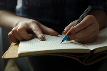 A girl is holding a notebook on her lap and writing