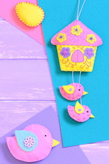 Happy Easter or spring background. Homemade vibrant felt Easter diy on wooden background with empty copy space for text. Felt house, bird and egg on a table. Top view. Vertical photo
