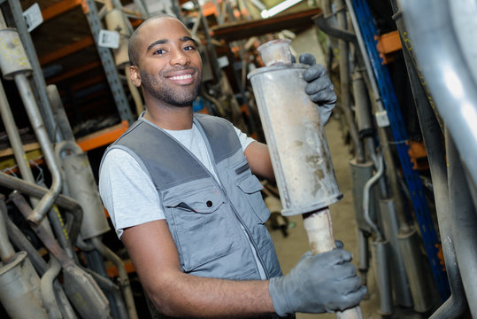 mechanic holding spare parts exhaust pipe