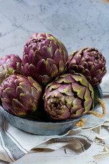 Fresh big Romanesco artichokes green-purple flower heads ready to cook