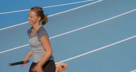 Female Track and Field Athlete running Relay Race with Baton in hand - Powered by Adobe