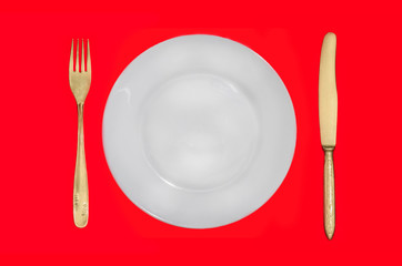 knife, fork and plate on a red background