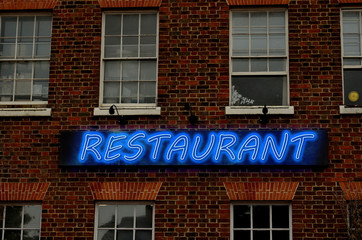 Fototapeta na wymiar Glowing neon letter on brick wall saying restaurant. The text restaurant is written using image processing software. It consist 6 layers