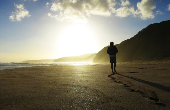 Young man walking down Johanna beach alone on sunset
