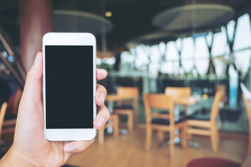 Mockup image of hand holding black mobile phone with blank white screen in cafe