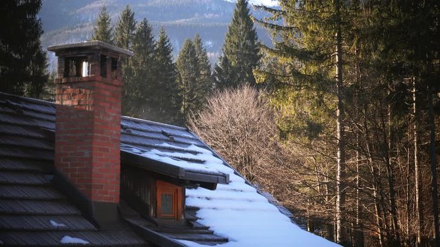 Mountain cottage chimney in winter morning, establishing shot