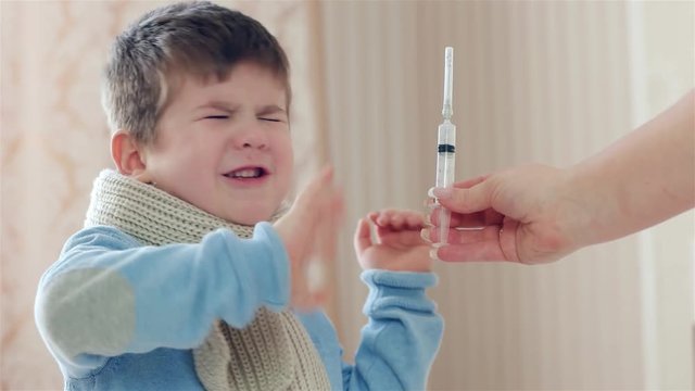 medical instruments for injections, child is afraid of the injection, small boy is sick, medicine syringe in hand, protest against care, kid is afraid and crying, treatment,