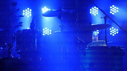 The scene with the drum kit and beautiful searchlights in blue colors