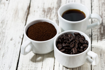Three types of coffee - ground, grain and beverage in cups on white background
