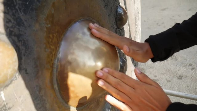 Female Hands Stroking the Religious Gong in Buddhist Temple for Good Luck. HD. Phuket, Thailand.