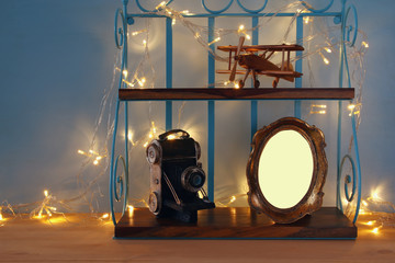 Vintage shelf with old wooden plane toy, decorative camera and blank photo frame