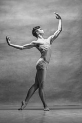 The male ballet dancer posing over gray background