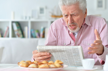 Elderly man reads a newspaper