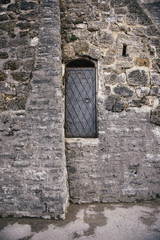 Fototapeta na wymiar Black iron door with handle in ancient stone wall