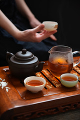Tea in cups, glass jug and teapot, hand holding cup