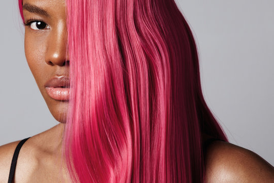 closeup black woman's portrait with a half of a face covered by pink hair