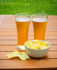 Light  beer with potato chips on  wooden table