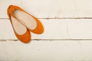 Orange women's shoes (ballerinas) on wooden background.