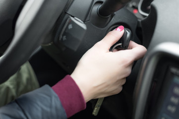 Closeup inside vehicle of hand holding key in ignition, start engine key