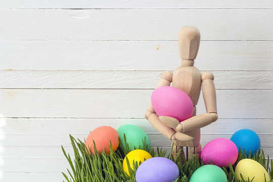 A wooden dummy holds an Easter egg.