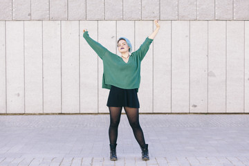 cheerful teen androgynous woman with blue dyed hair and arms wide open