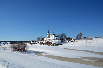 View to Russian Orthodox "St. George" Church was founded in 1806 year on the shore of frozen Chusovaya river in Sloboda village, Sverdlovsk region, Russia in the beginning of Spring.