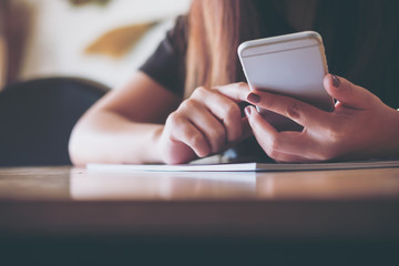A woman holding and using the smart phone in modern cafe