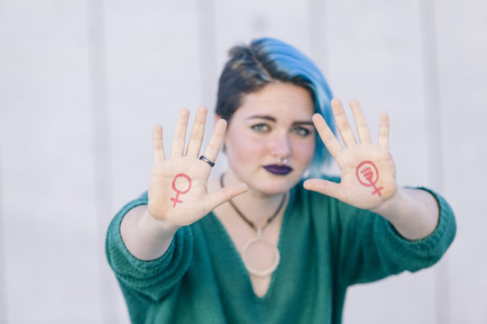 strong young woman fighting for gender equality with the feminist symbol on her hand