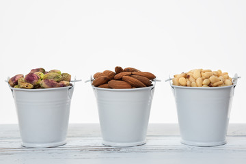Buckets of nuts on the wooden table with white background