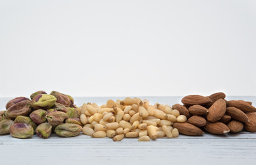 Fototapeta na wymiar Pine nuts, almonds and pistachios on the wood