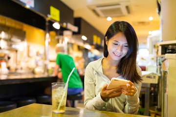 Woman checking on mobile phone in Japanese restaurant