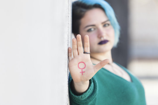 strong young woman fighting for gender equality out of focus with the feminist symbol on her hand