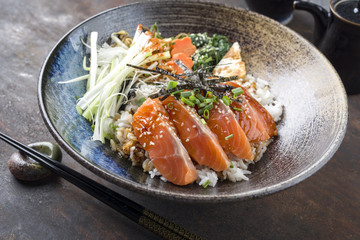 Traditional Salmon Sashimi Donburi with Rice and Vegetable as close-up in a bowl