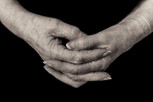 Close up of a pensioner's hands clasped. Monochrome.