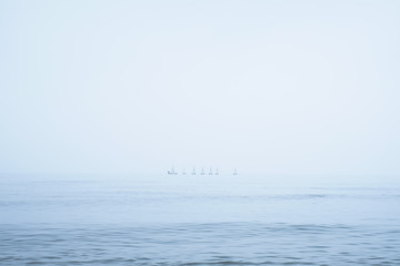 Obraz na płótnie Canvas 霧の立ち込めた海を進む複数のヨット