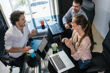 Team von Kreativen in einer Agentur unterhalten sich im Büro am Schreibtisch
