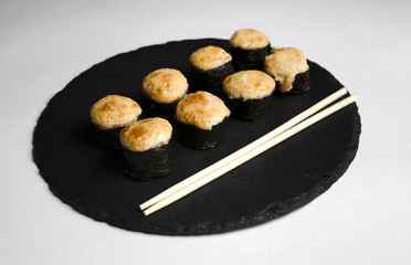 Baked sushi on slate plate with chopsticks