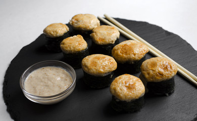 Baked sushi on slate plate with chopsticks