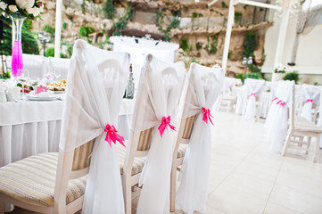 Wedding guest chairs with pink ribbons at wedding hall.